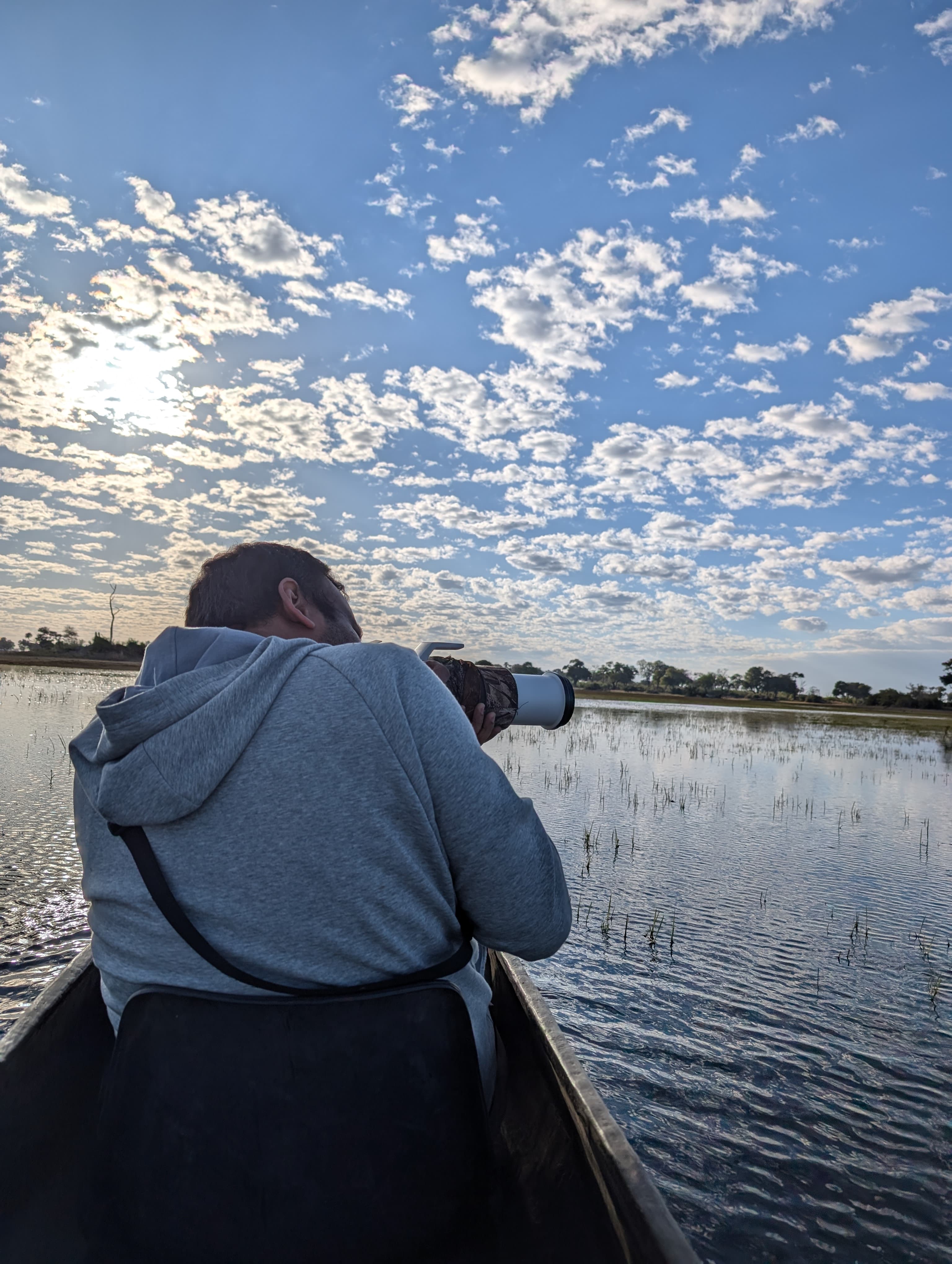 Kshetrajna photographing wildlife from a boat on the Okavango Delta at dawn
